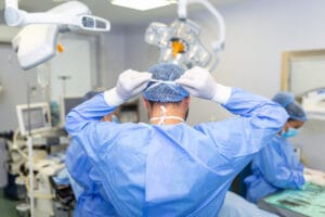 Vista traseira do cirurgião masculino usando máscara cirúrgica na sala de operações do hospital